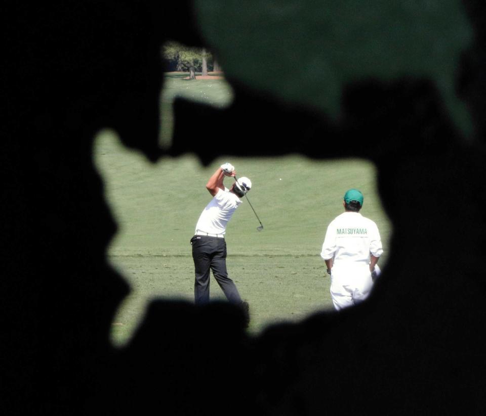 　マスターズのマークをかたどった穴の向こうで打ち込む松山英樹（中央）