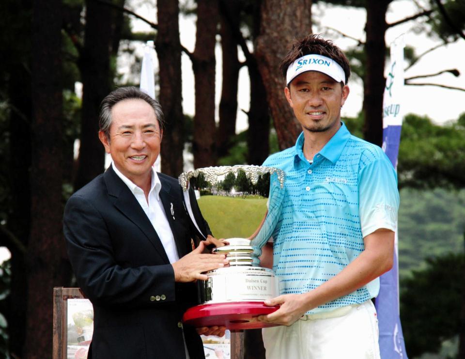 　平山善裕大会会長（左）から優勝カップを受け取る星野英正