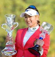 　優勝カップを手に、カメラに向かってウインクする