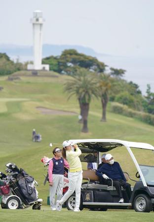 　白い灯台が見える１３番でセカンドショットを放つ稲見萌寧（手前）。後方左はＬＰＧＡ相談役の樋口久子氏（撮影・開出牧）