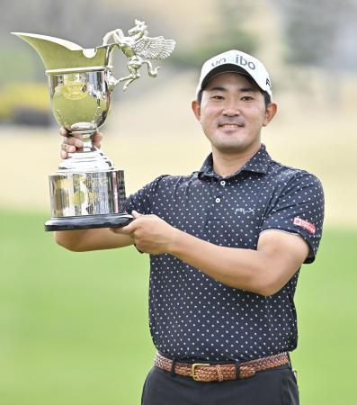 　通算２３アンダーで優勝し、カップを手に笑顔の金谷拓実＝東建多度ＣＣ名古屋