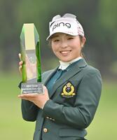 　通算１１アンダーで初優勝を果たし、トロフィーを手に笑顔の佐久間朱莉