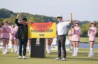 　大会主催者の前澤友作氏（左）から優勝賞金パネルを受け取りガッツポーズを決める小西たかのり（撮影・開出牧）