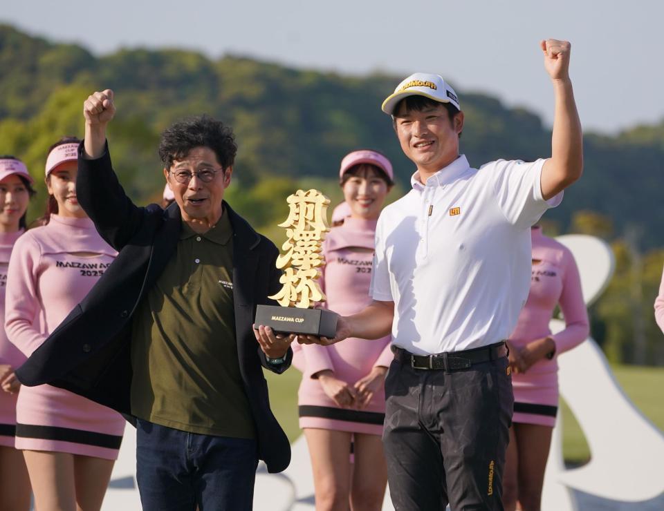 　大会主催者の前澤友作氏（左）から優勝トロフィーを受け取りガッツポーズを決める小西たかのり（撮影・開出牧）