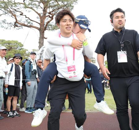 　自力で歩くことができず、関係者におぶられて、カートまで運ばれる藤田さいき（撮影・西岡正）