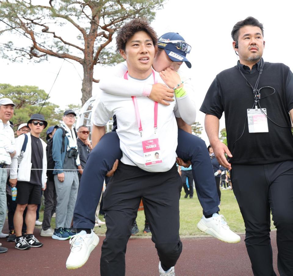 　自力で歩くことができず、関係者におぶられて、カートまで運ばれる藤田さいき（撮影・西岡正）