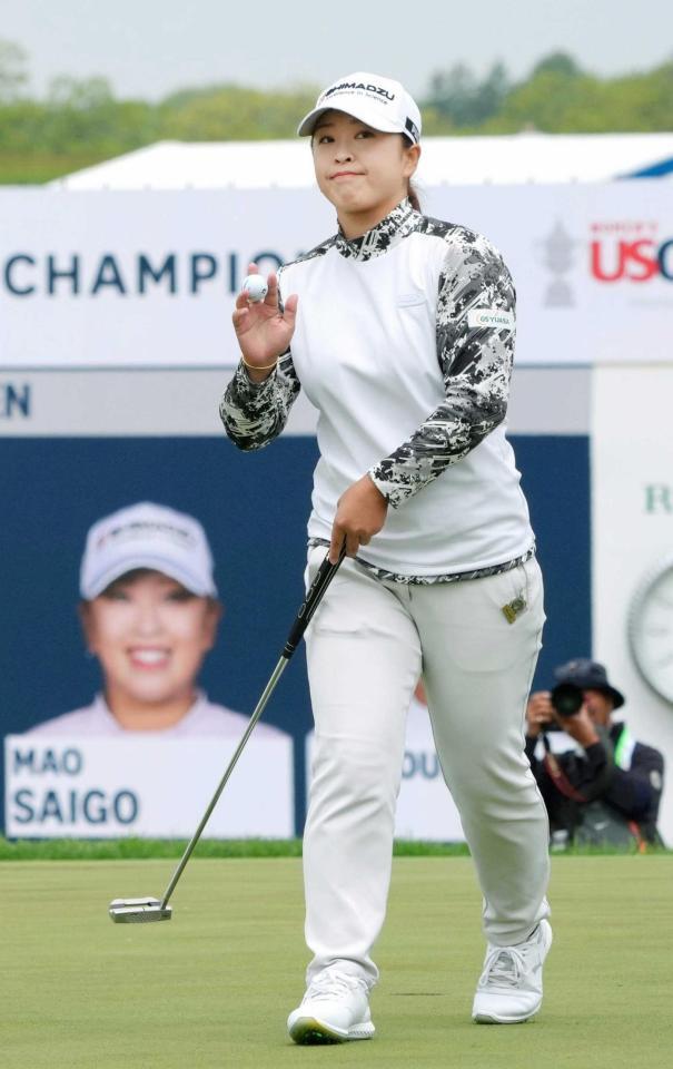 　第２ラウンド、１８番でバーディーを決め、拍手に応える西郷真央（共同）