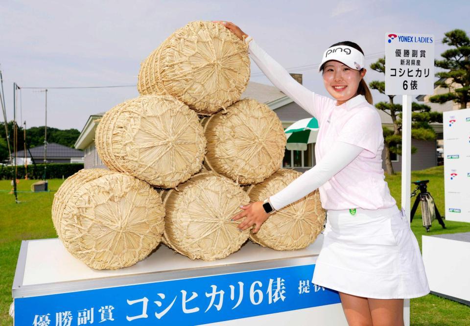 　通算１５アンダーで初優勝し、副賞の米俵の前でポーズをとる高野愛姫