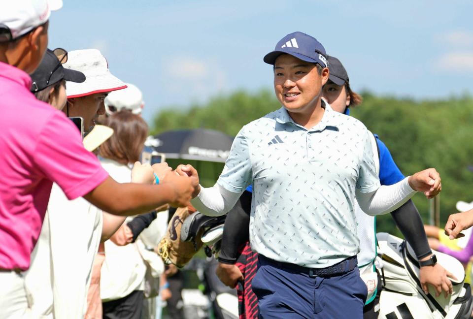 　ホールアウトし、ギャラリーとタッチを交わす吉田泰基。通算１７アンダーで２位