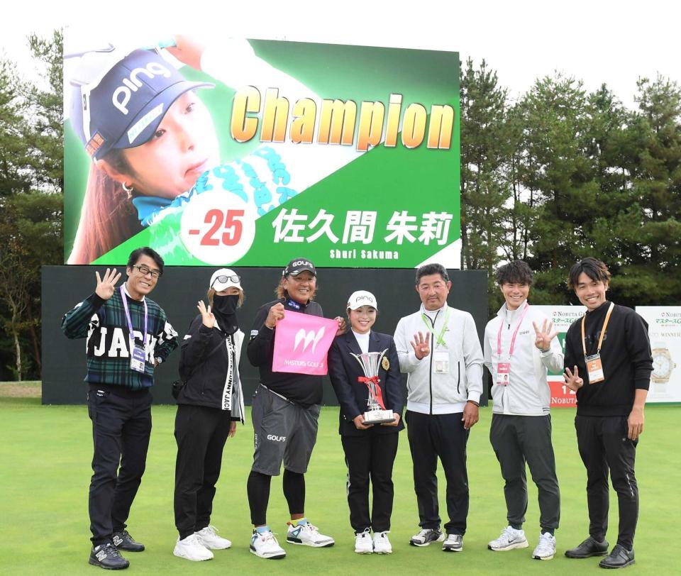 　通算２５アンダーの大会新記録で圧勝し、関係者と記念撮影をする佐久間（中央）