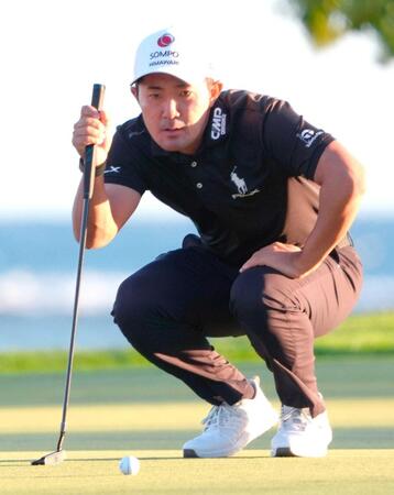 　１６番でパットのラインを読む金谷拓実（共同）