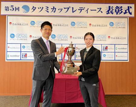 ㈱タツミコーポレーション・李煥辰代表取締役社長（左）から優勝トロフィーを受け取る安本美咲