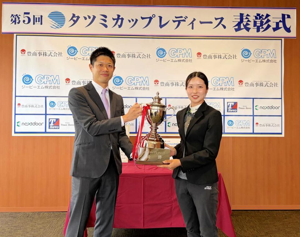 ㈱タツミコーポレーション・李煥辰代表取締役社長（左）から優勝トロフィーを受け取る安本美咲