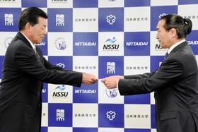 　松浪健四郎理事長（右）から客員教授委嘱状を受け取る室田プロ（２０１４年４月７日・日体大）