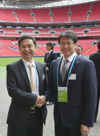 　ウェンブリー競技場で握手する男子の関塚監督（右）と女子の佐々木監督（共同）