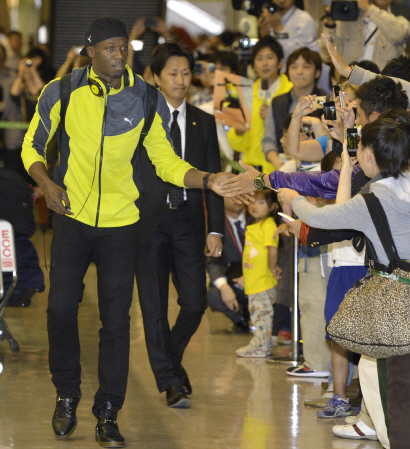 　待ち構えたファンとタッチを交わすウサイン・ボルト（左）＝成田空港
