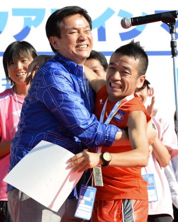 　表彰式で森田健作千葉県知事（左）と抱き合う猫ひろし＝千葉・木更津市