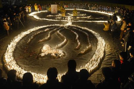 　阪神・淡路大震災の追悼集会で、ろうそくをともして犠牲者の冥福を祈る人たち　（下）犠牲者の冥福を祈り、ろうそくをともす女の子＝１６日夜、兵庫県伊丹市の昆陽池公園