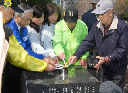 　「希望の灯り」から分灯する人たち＝神戸市中央区の東遊園地