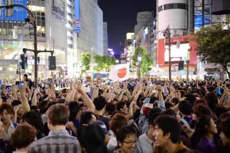 　日の丸を掲げ喜ぶサッカー日本代表サポーターら＝東京都渋谷区