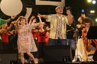 　エンディングで、他の出演者とともに踊る大竹しのぶ（左）と熱唱するＢＥＧＩＮの比嘉栄昇＝沖縄県嘉手納町の兼久海浜公園特設会場