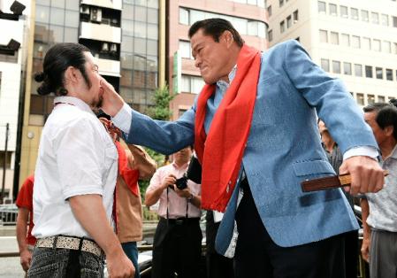 事務所前に集まった通行人に闘魂ビンタを見舞うアントニオ猪木氏＝東京・港区