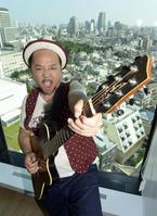 　東京の街並みをバックにポーズを決めるマキタスポーツ＝東京都渋谷区のビクター本社（撮影・開出　牧）