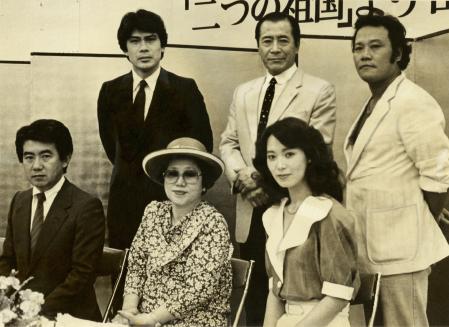 　８３年６月、ドラマ「山河燃ゆ」の記者会見に出席した山崎豊子さん（前列中央）と松本幸四郎（後列左）