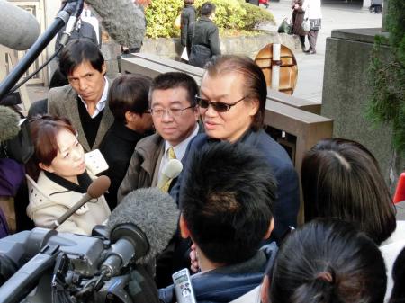 　裁判終了後に報道陣に対応する甲斐智陽氏（中央）と伊藤芳朗弁護士（左から３人目）＝東京地裁