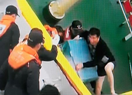 　韓国海洋警察庁が公開した１６日に撮影した映像で、セウォル号の沈没前に下着姿で警備艇に乗り移るイ・ジュンソク船長（中央）（ニュースＹの画面から・共同）