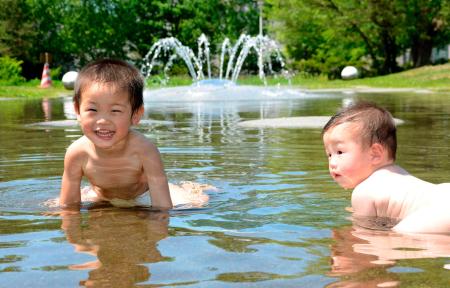 　厳しい暑さとなり、公園で水浴びをする幼児＝北海道旭川市