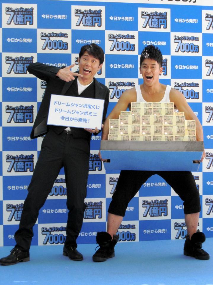 ７億円を持ち上げる武井壮（右）と原田泰造＝東京・西銀座チャンスセンター