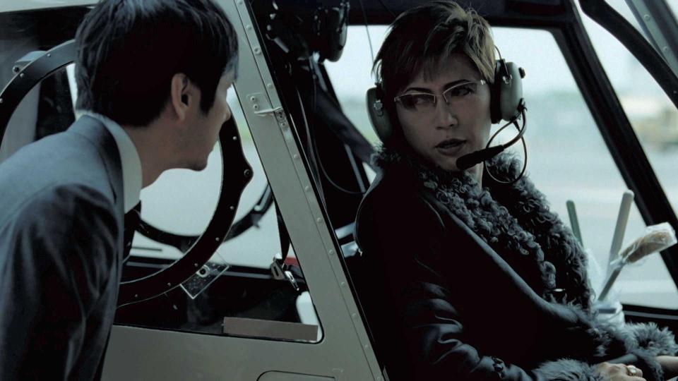 　横の座席にトイレブラシを置きヘリコプターに乗り込むＧＡＣＫＴと、置いて行かれる西島秀俊（左）