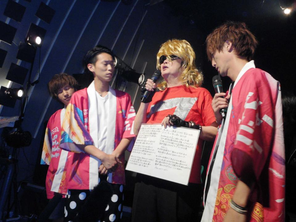　自作の歌詞カードを示し、脱退の理由を説明する大木凡人（右から２人目）