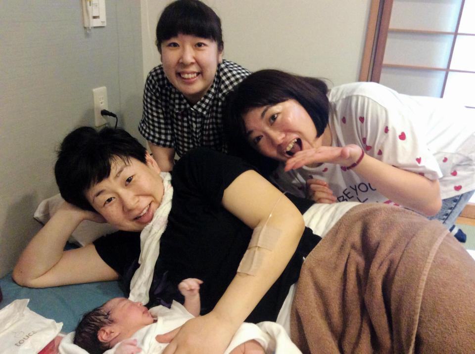 生まれたばかりの長男を抱く大島美幸（手前）と、出産に立ち会った村上知子（後方左）、黒沢かずこ（同右）＝都内の病院