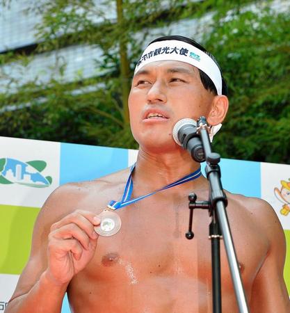 報告会でフィンスイミングで獲得した銅メダルを誇らしげにかかげる春日俊彰＝埼玉・所沢市役所（撮影・園田高夫）