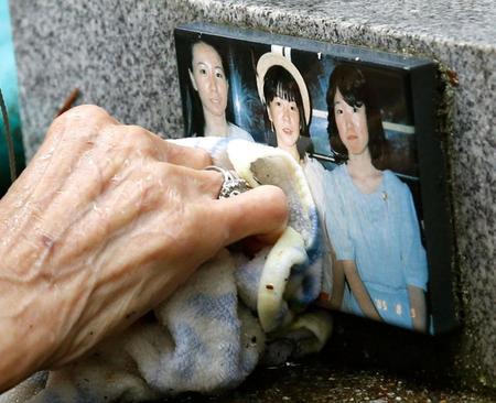 亡くなった娘たちの写真が張られた「御巣鷹の尾根」の墓標を掃除する田淵輝子さんの手＝群馬県上野村