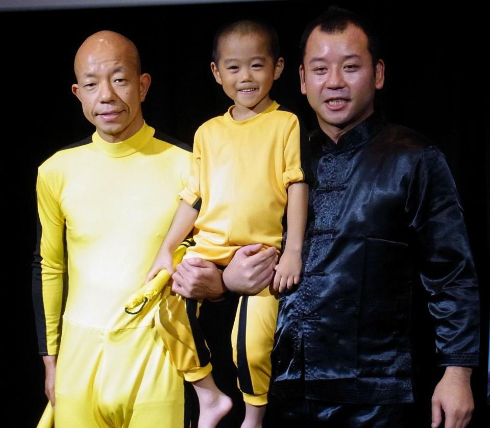 ブルース・リーとジャッキー・チェンになりきったバイきんぐの小峠英二（左）、西村瑞樹（右）に抱えられる今井竜惺くん＝東京・青山