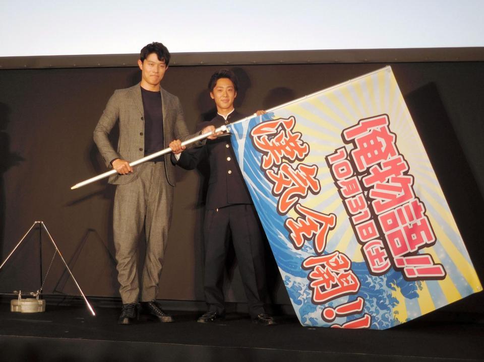 高校に記念旗を贈呈した鈴木亮平（左）＝東京・神田錦町