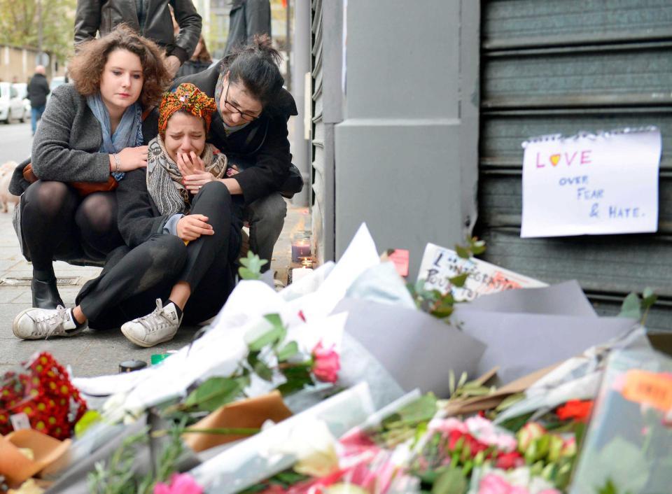 銃撃されたカンボジア料理店付近で、泣く女性＝１４日、パリ（ゲッティ＝共同）