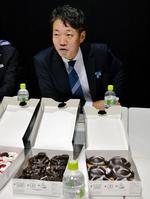 メルセデス・ベンツのエンブレムがデザインされたドーナツの前で囲み取材に応じる上野金太郎社長