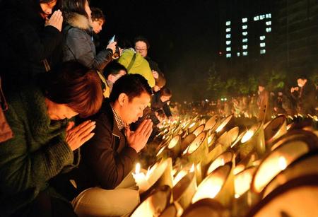 　竹灯籠のろうそくに鎮魂の祈りをささげる参列者たち＝１７日午前５時５４分、神戸市中央区加納町６、東遊園地（撮影・中西幸大）
