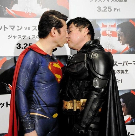 スーパーマンにふんした寺門ジモン（左）とチューをするバットマンにふんした上島竜兵＝東京・ワーナーブラザーズ試写室