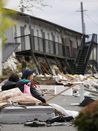 　倒壊したアパートの前で、毛布にくるまる住民の学生ら＝熊本県南阿蘇村