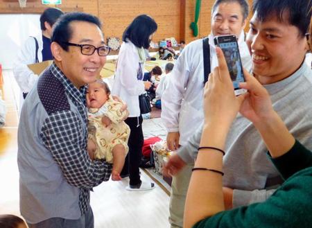 　避難所近くで車中泊をしているという家族の撮影に応じる歌手さだまさしさん＝２３日午後、熊本県西原村