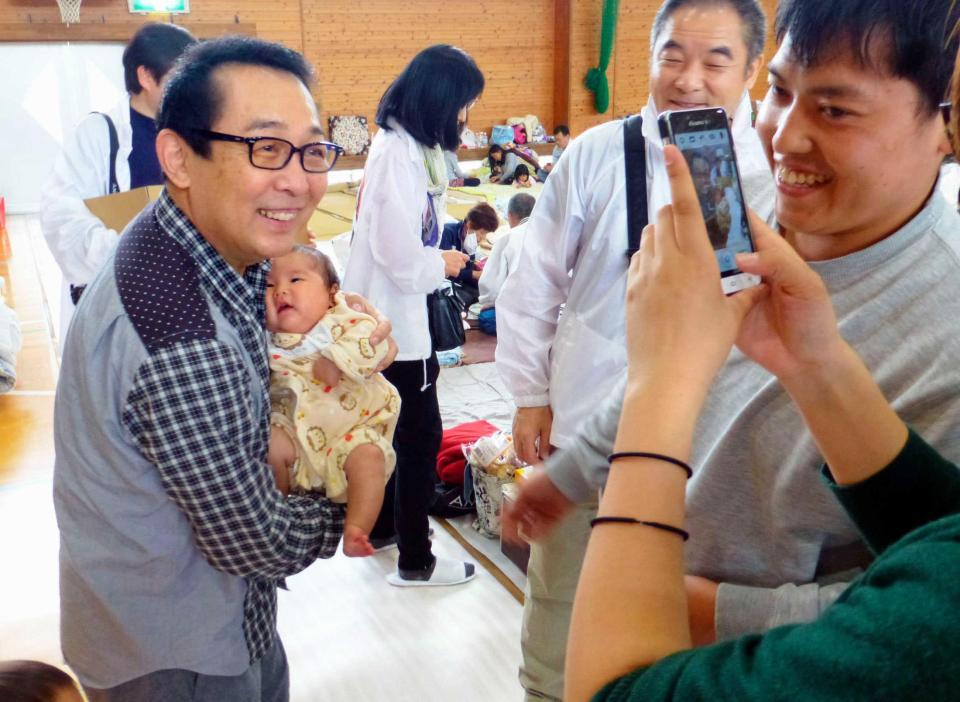 　避難所近くで車中泊をしているという家族の撮影に応じる歌手さだまさしさん＝２３日午後、熊本県西原村