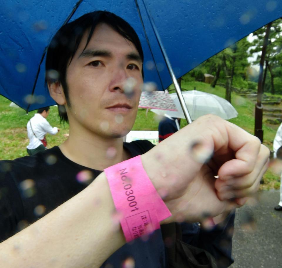 １番のリストバンドを見せる男性＝午前東京都千代田区の日比谷公園（撮影・出月俊成）