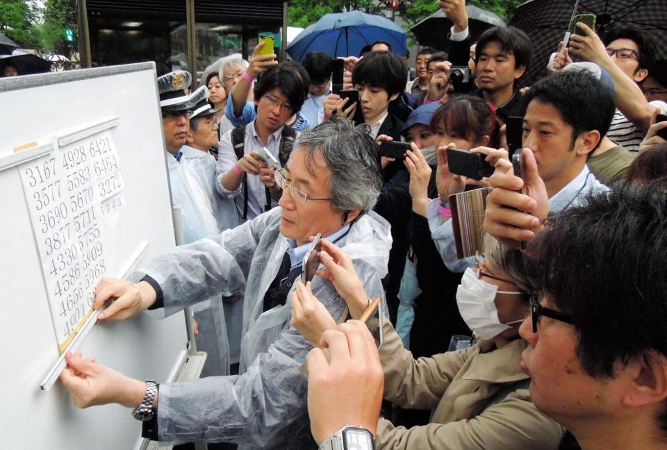 傍聴券の当選番号を貼り出す関係者とカメラに納める人々＝東京・日比谷公園（撮影・村中拓久）