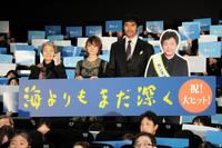 「海よりもまだ深く」の初日舞台あいさつに出席した（左から）樹木希林、真木よう子、阿部寛と、カンヌに滞在中の是枝監督のパネル＝東京・新宿ピカデリー