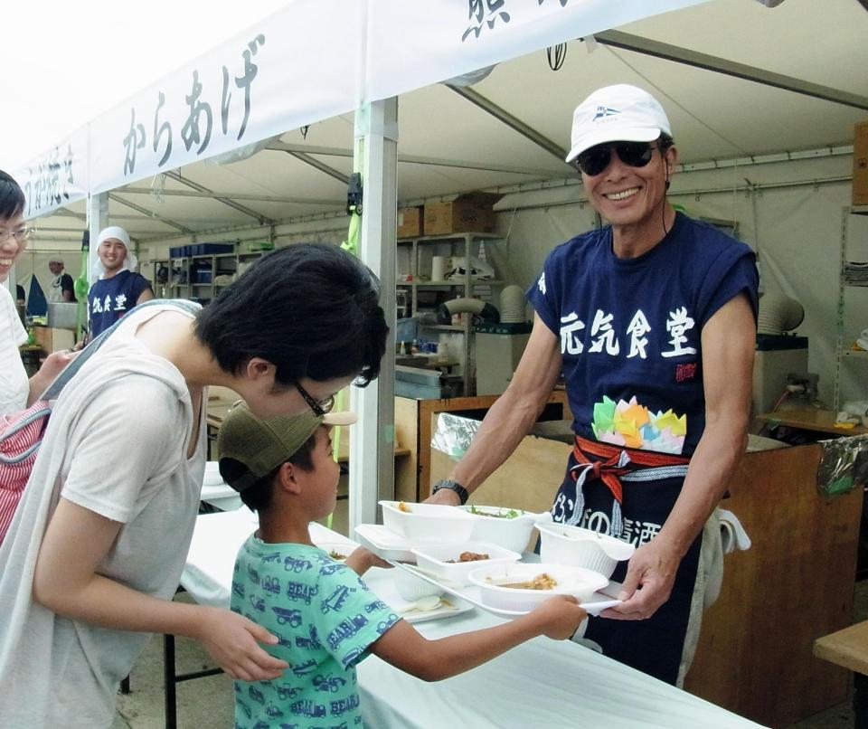 男の子に食事を渡す舘ひろし＝熊本県・益城町